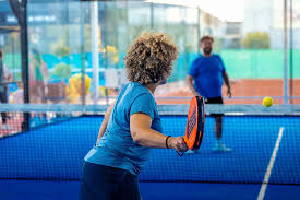 een vrouw met krullen die de bal terug over het net slaat